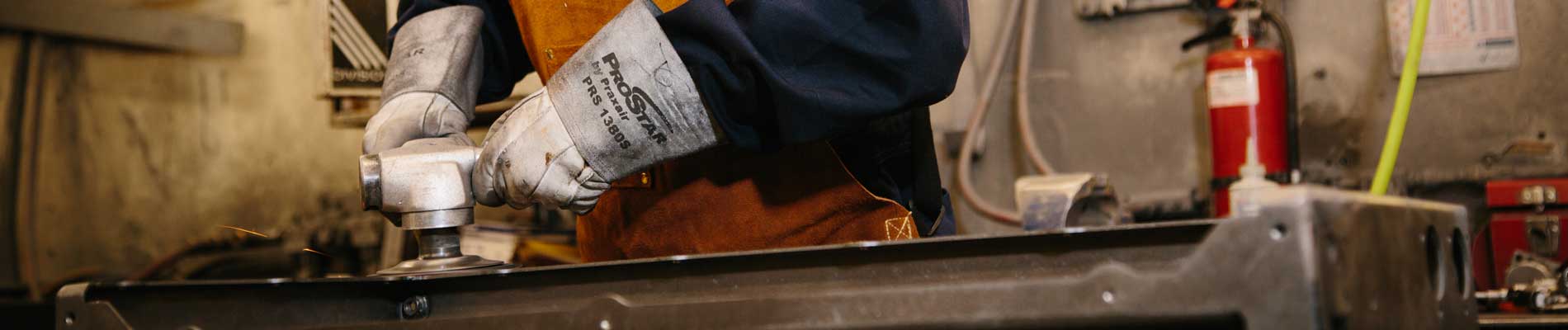 Wesgar's Leadership Team page banner image: gloved hands using grinder on sheet metal product