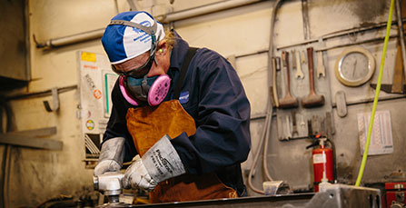 sheet metal worker wearing safety equipment while grinding metal products